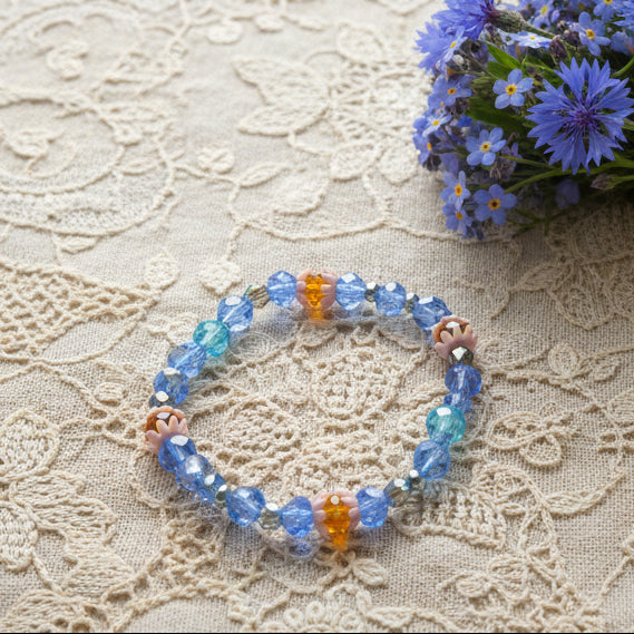 Beaded bracelet with blue, orange, and clear beads on a gray background