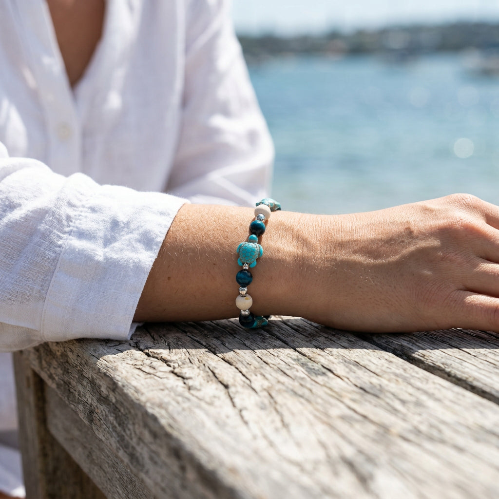 A beaded stretch bracelet featuring turquoise and dark blue beads, light wood beads, and silver spacer beads, displayed on a plain light gray background.