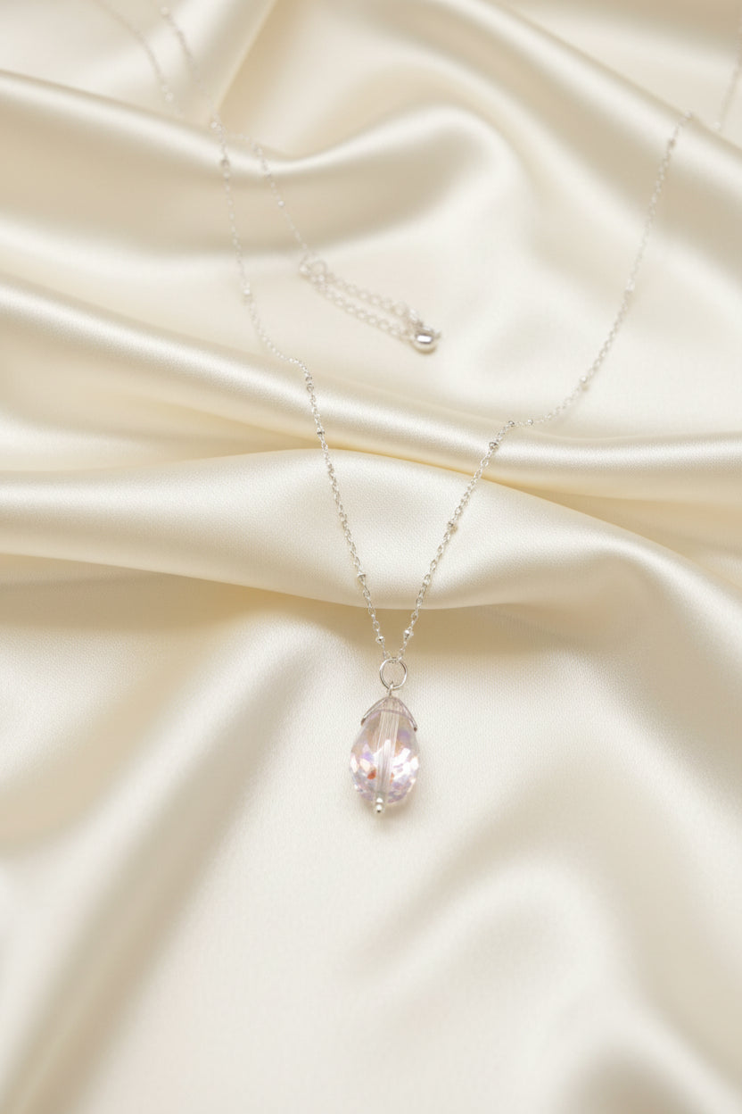 A silver-tone chain necklace with a teardrop-shaped iridescent pendant displayed on a black velvet jewelry bust against a white background.