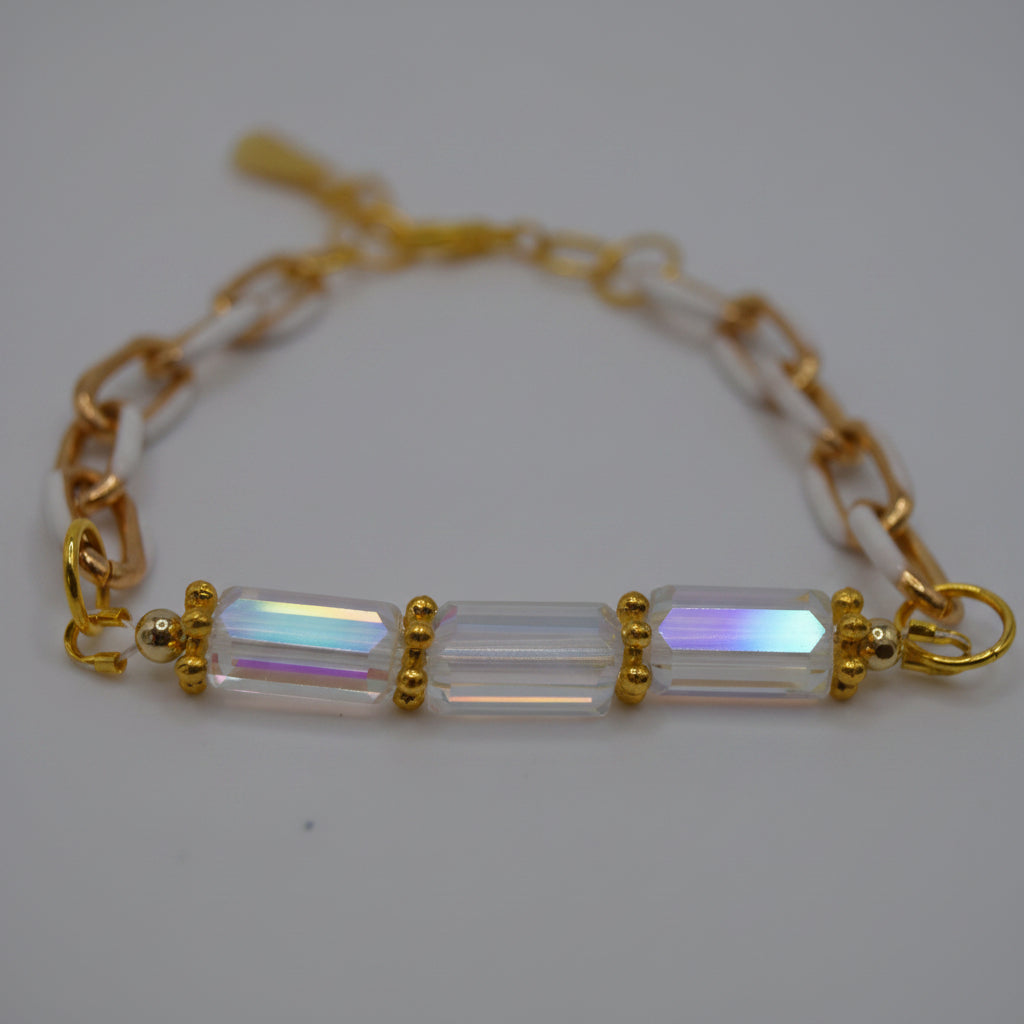 A gold chain bracelet featuring three rectangular iridescent glass beads set in gold at the center, photographed on a plain light gray background.