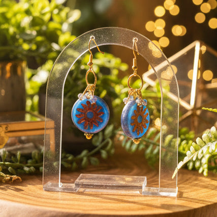 Pair of blue and gold earrings on a gray background