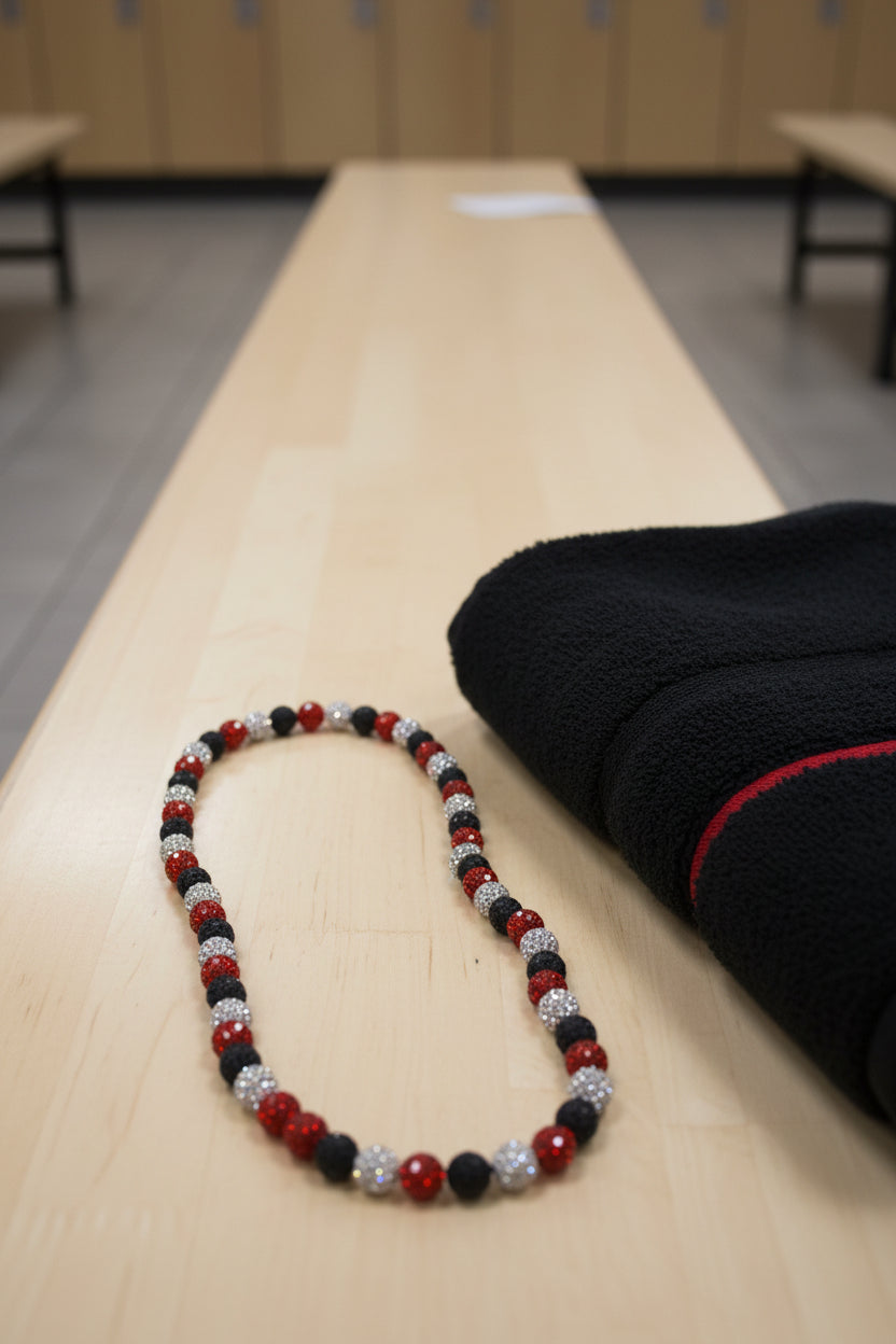 A beaded necklace with alternating red, black, and silver faceted beads, arranged in a loop on a plain light gray background.