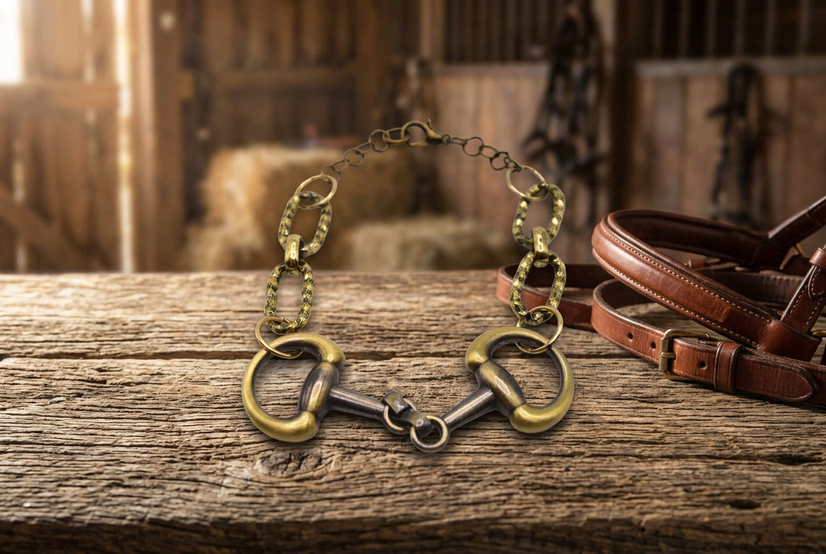 A horsebit bracelet featuring a gold and silver-tone metal design with two horsebit links at the ends and a chain link extension, shown on a plain light gray background.