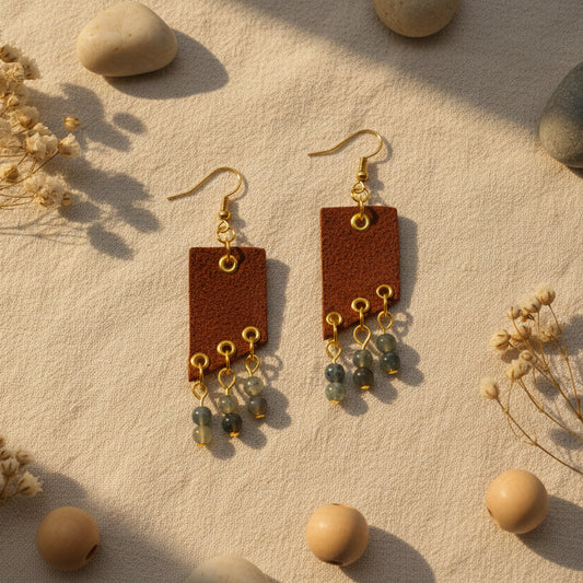 Brown leather earrings with gold hooks and green beads on a white background