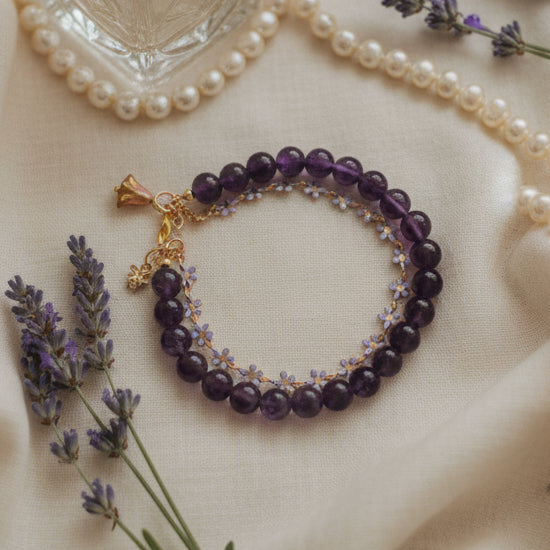 Purple beaded bracelet with gold accents on a gray background