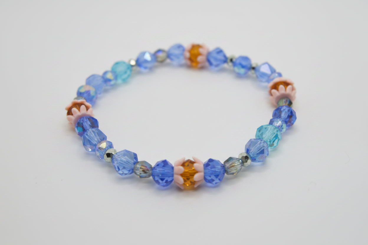 Beaded bracelet with blue, orange, and clear beads on a light gray background