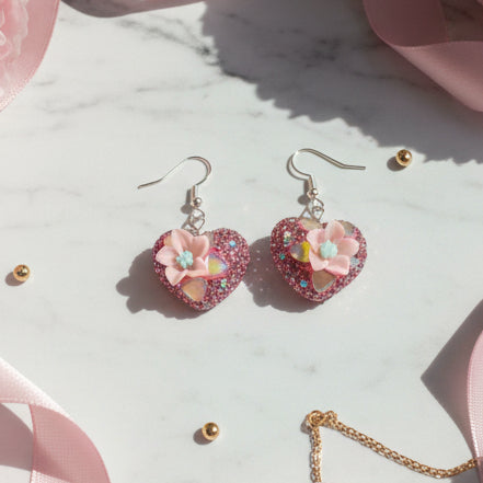 Heart-shaped earrings with floral designs on a gray background