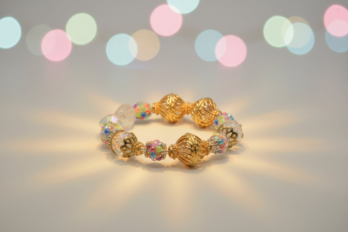 A beaded stretch bracelet featuring gold filigree spacers, clear faceted beads, and multicolor iridescent beads, displayed on a neutral gray background.