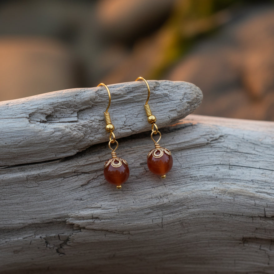 Pair of gold earrings with red stones on a gray background