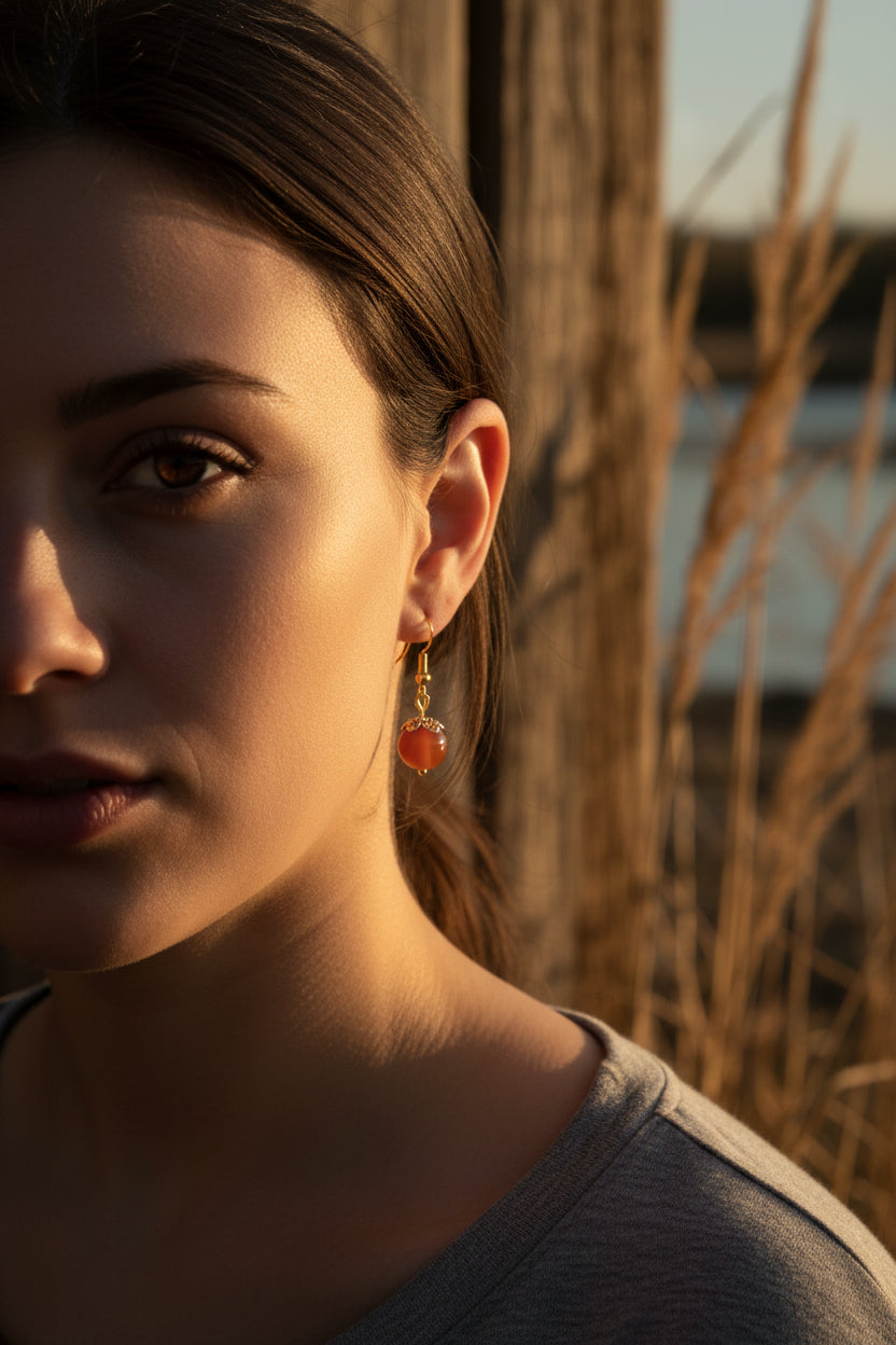 Pair of earrings with red beads and gold hooks on a gray background