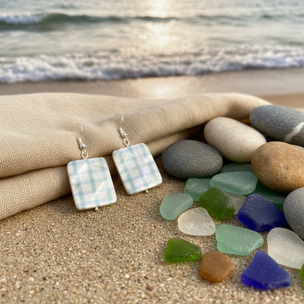 A pair of rectangular drop earrings with a green and beige plaid pattern, suspended from silver fishhook wires, displayed against a neutral gray background.