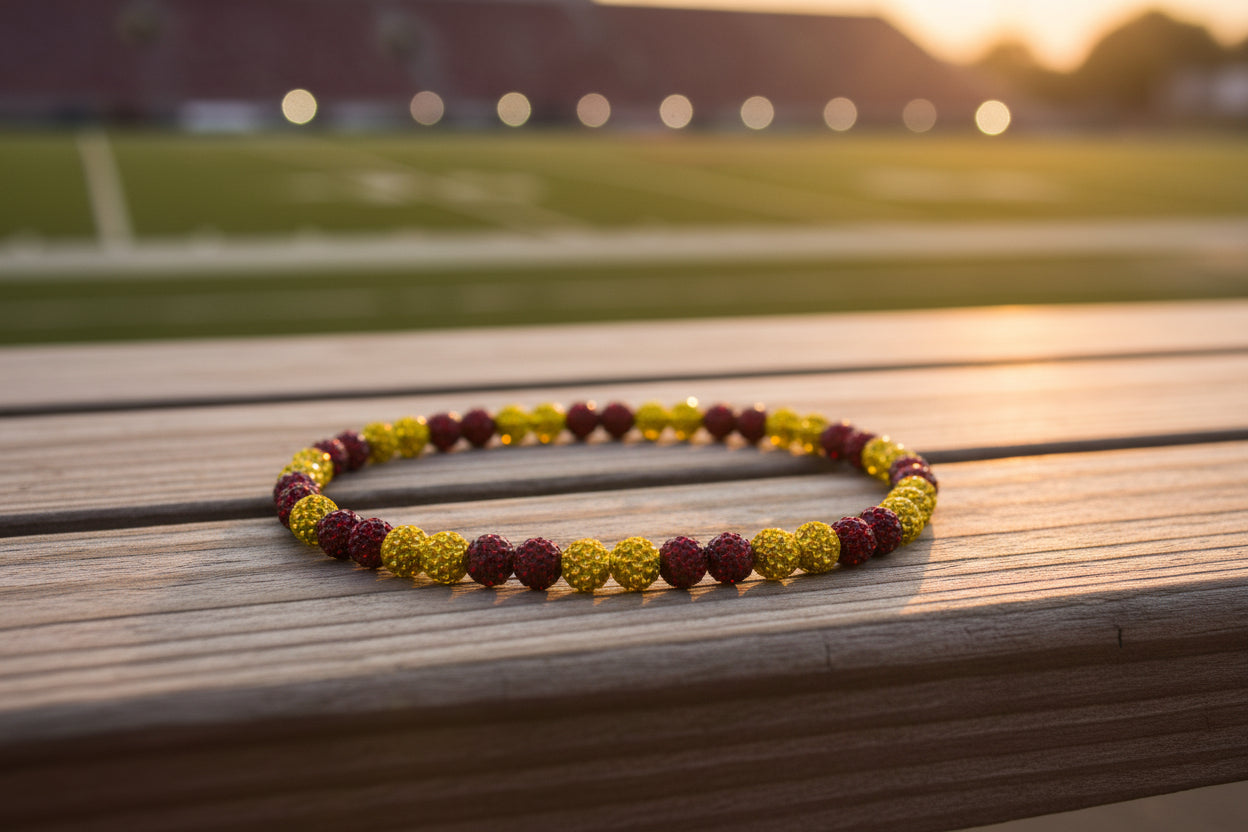 A beaded necklace made of alternating dark red faceted beads and metallic gold textured beads, arranged in a circle on a plain white surface.