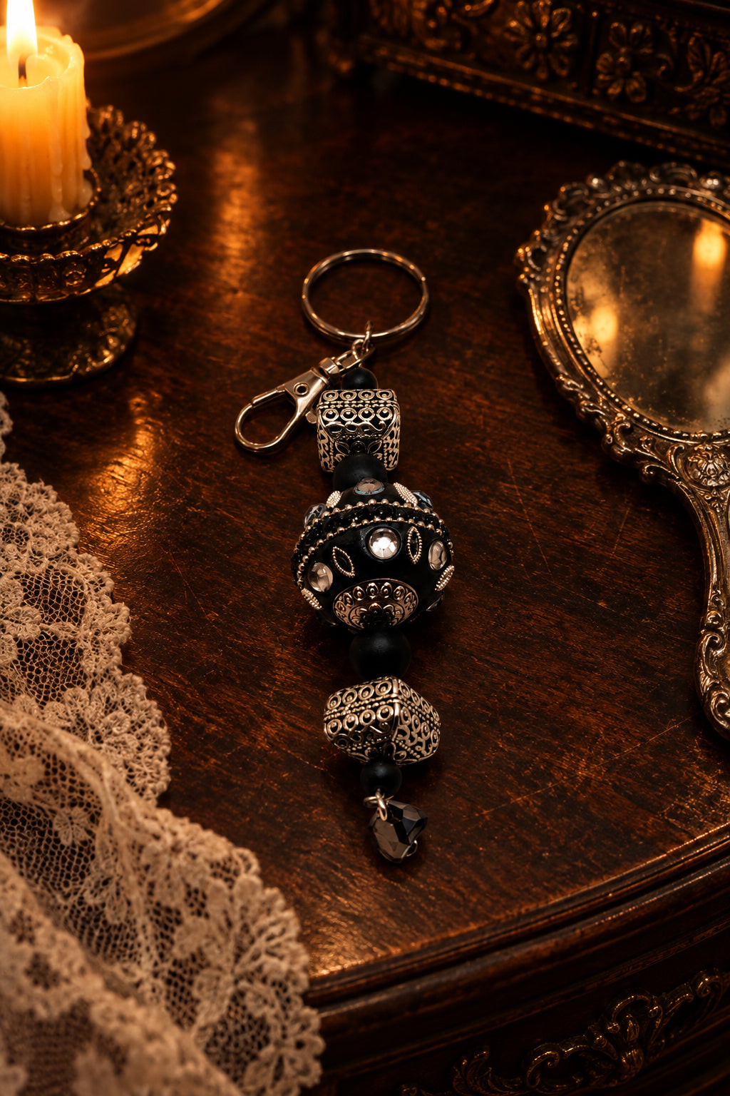 A beaded keychain featuring black and silver-toned beads, textured metal spacer rings, and a lobster clasp on a plain light gray background.