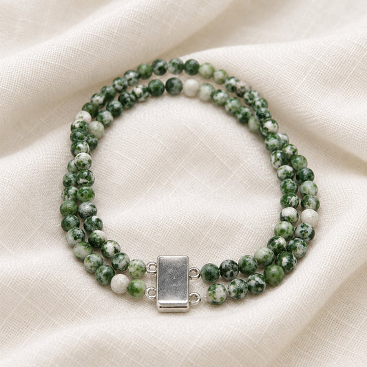A beaded wrap-style bracelet made of marbled green and white beads with a rectangular silver clasp, photographed on a plain light background.