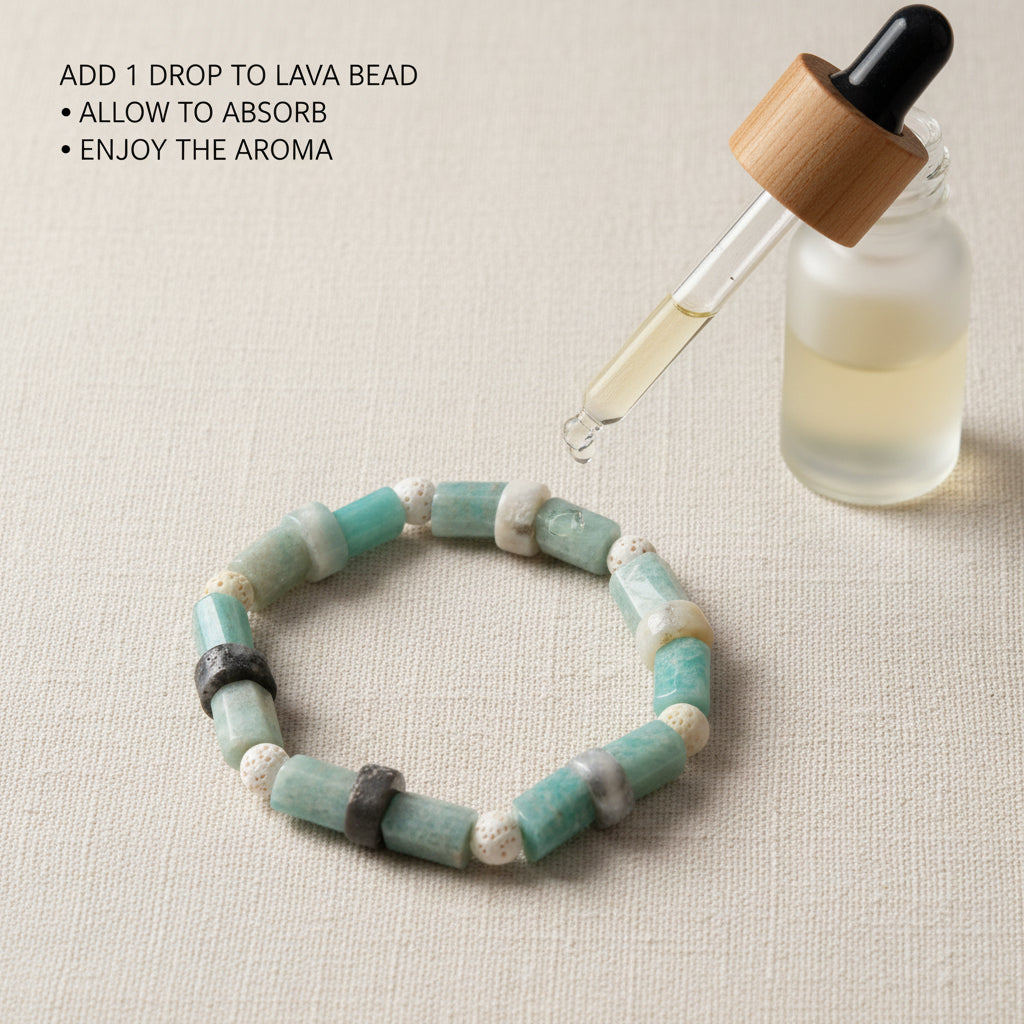 A beaded stretch bracelet made of cylindrical and round beads in shades of turquoise, sage green, cream, and gray, with two dark metallic spacer beads, displayed on a neutral light gray background.