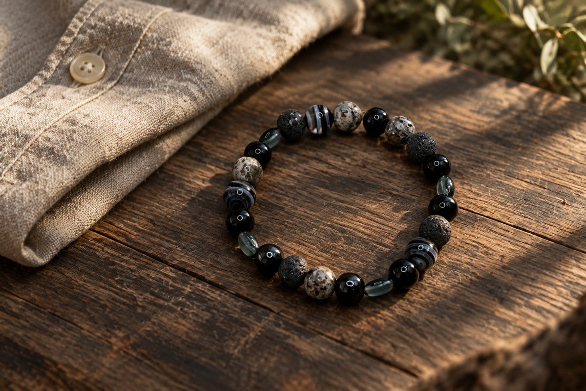 A beaded stretch bracelet made of black, gray, and white marbled beads, displayed on a neutral light gray background.