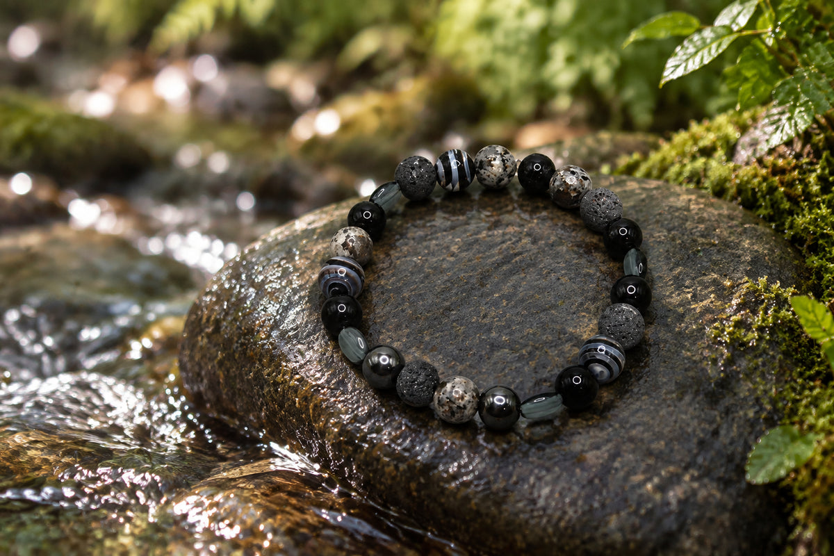 A beaded stretch bracelet made of black, gray, and white marbled round beads, displayed on a plain light gray background.
