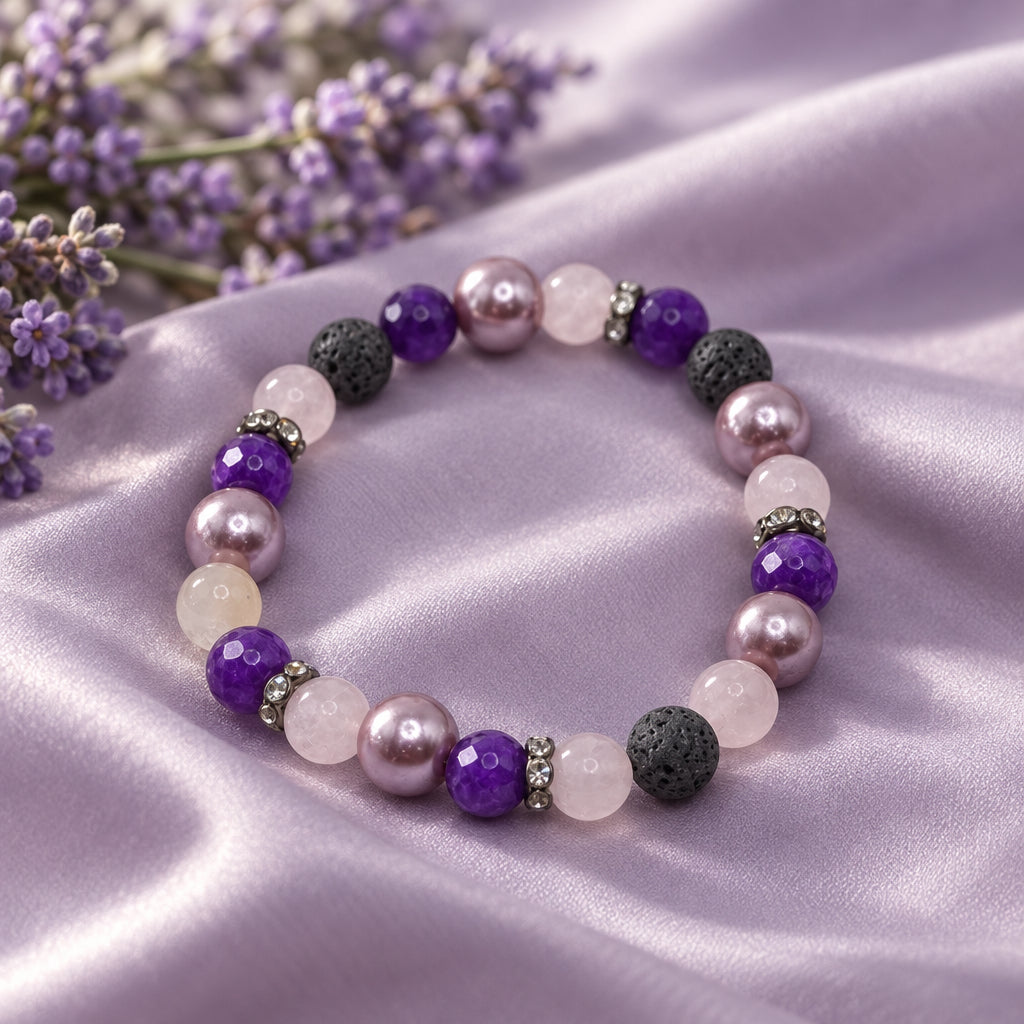 A beaded stretch bracelet featuring purple and lavender pearls, dark gray lava stone beads, and small metallic spacer beads, displayed on a neutral light gray background.