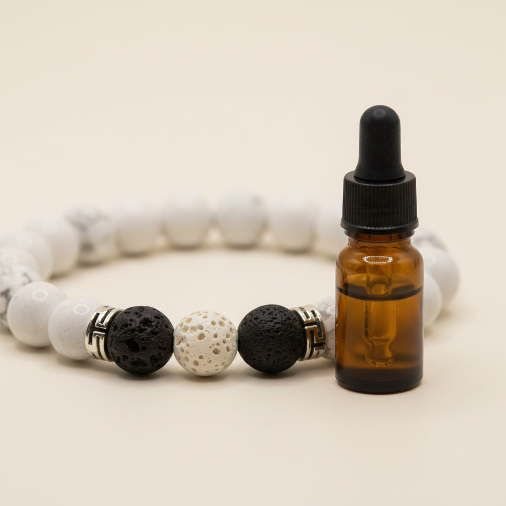 A beaded stretch bracelet featuring matte white and textured gray round beads, accented by a black lava stone, a white seed bead with gold speckles, and small gold spacer rings, shown on a neutral gray background.