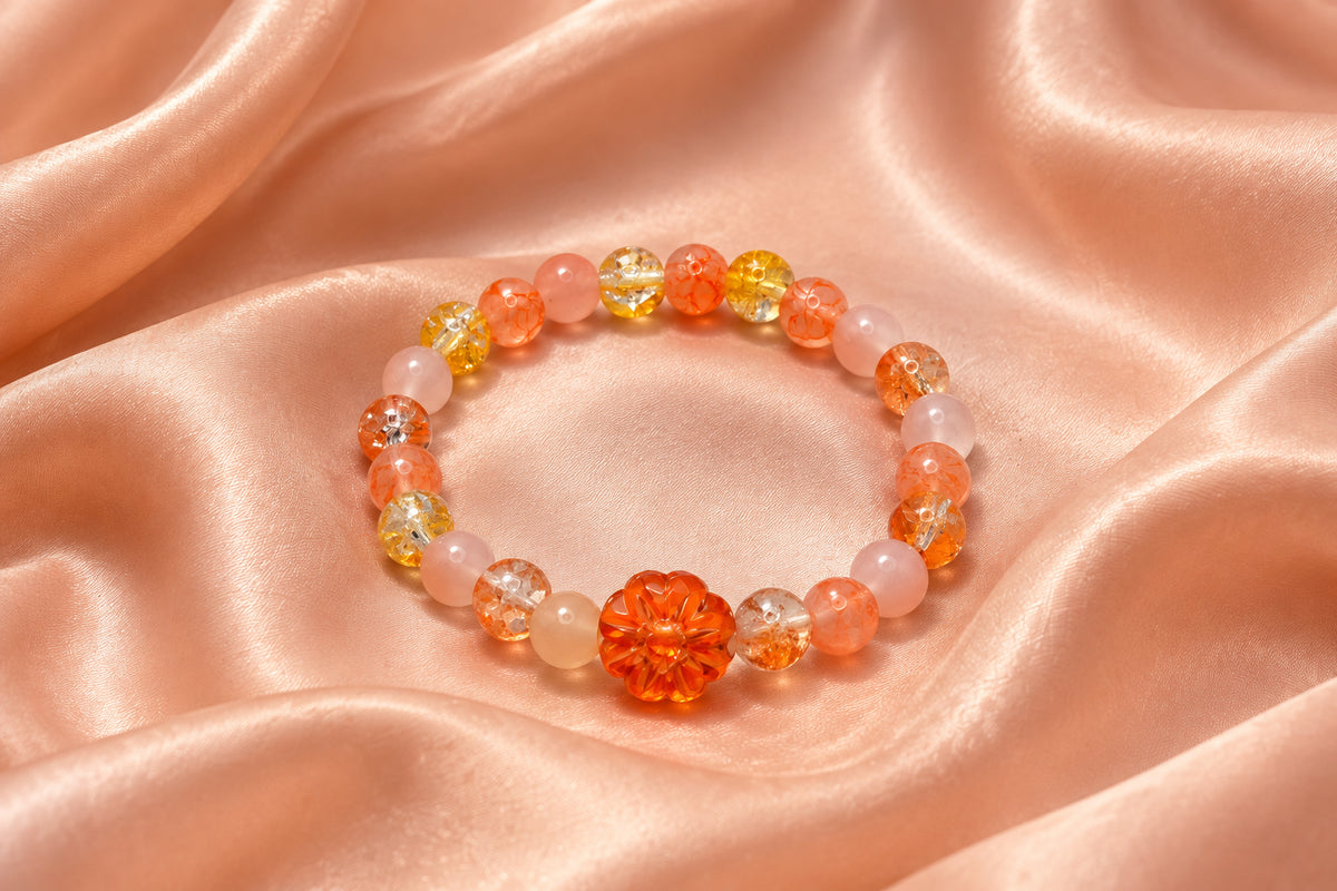 A beaded stretch bracelet featuring translucent peach, orange, and yellow beads, with a prominent textured orange flower-shaped bead at the center, displayed on a plain light gray background.