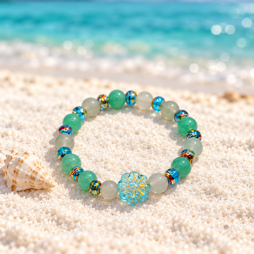 A beaded stretch bracelet featuring light blue, mint green, and translucent white beads, accented with small gold spacers and a central light blue floral bead, shown on a plain light gray background.