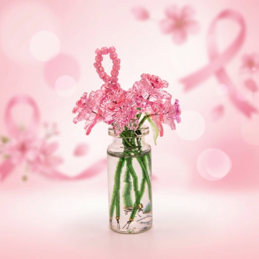 A small clear glass vial with water holding pink plastic flower stems with green stems, set against a white studio background.