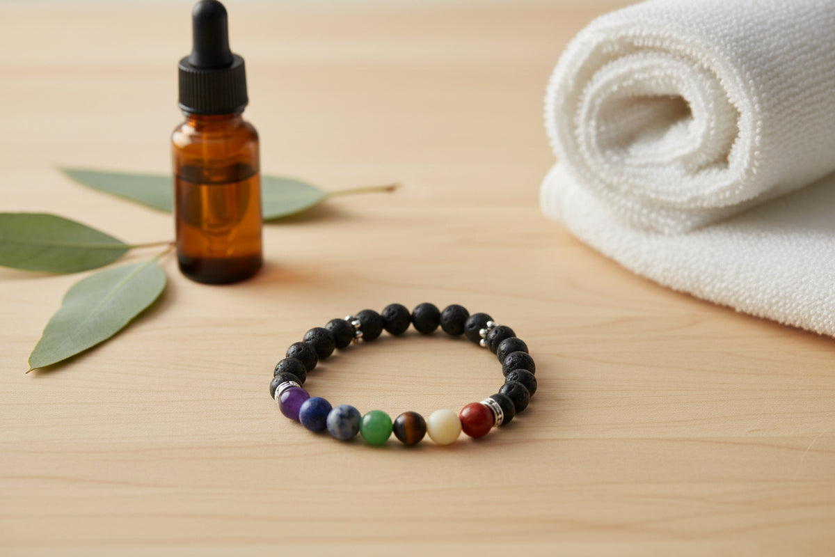 A beaded stretch bracelet featuring matte black round beads with a row of colorful, patterned chakra beads at the bottom, separated by small silver metallic spacers, shown on a plain light gray background.