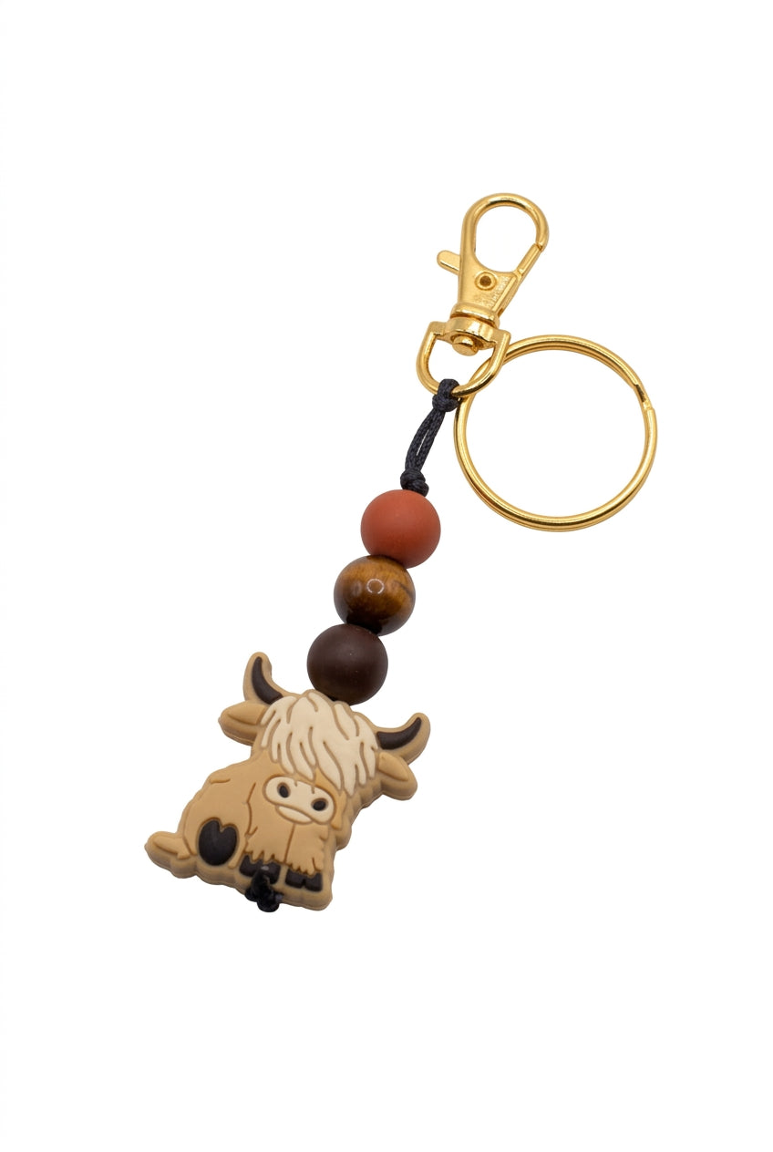 A small yellow keychain featuring a carved animal charm, a dark brown bead, and a red bead, with a yellow split ring, on a plain light gray background.