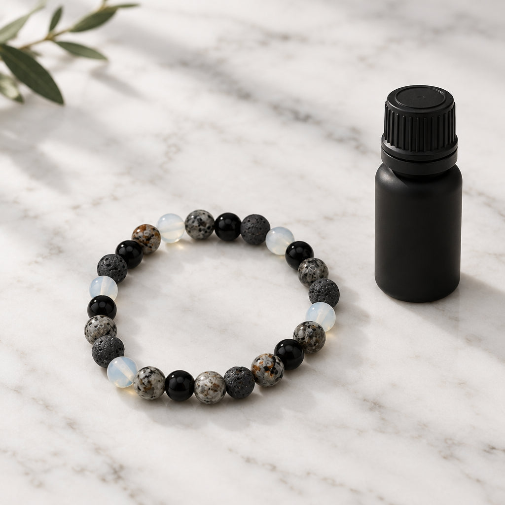 A beaded stretch bracelet made of round stone beads in black, gray, and white, arranged in a circle on a plain light gray background.