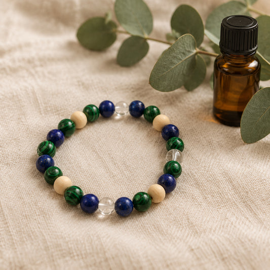 A beaded stretch bracelet featuring dark blue, forest green, and light beige wooden beads, accented with two clear faceted glass beads, displayed on a neutral gray background.
