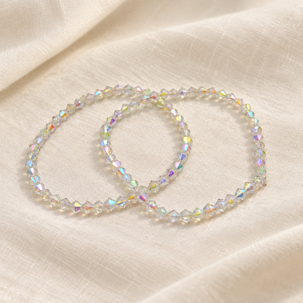 Two beaded stretch bracelets with iridescent, faceted beads arranged on a plain light gray background.