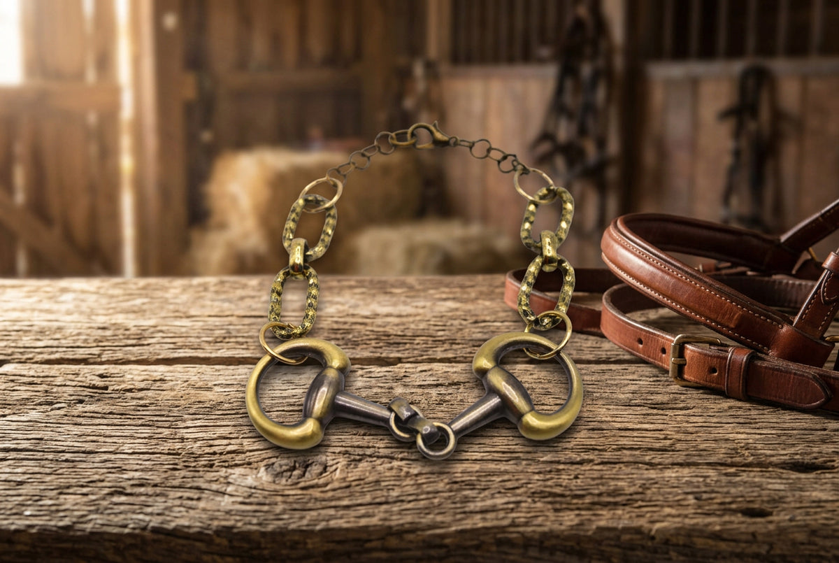 A horsebit bracelet featuring a gold and silver-tone metal design with two horsebit links at the ends and a chain link extension, shown on a plain light gray background.