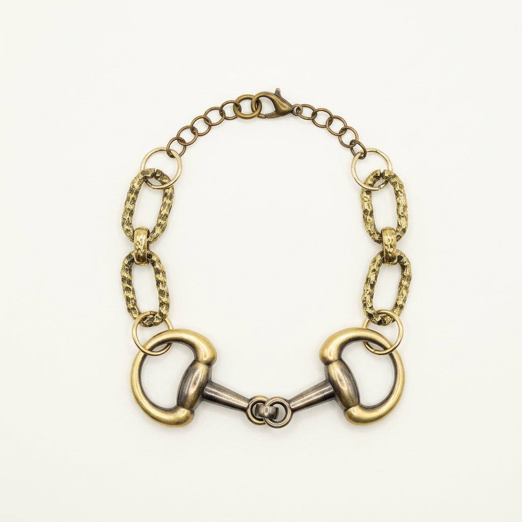 An antique-style horsebit bracelet with a gold and silver-tone metal finish, displayed on a plain light gray background.
