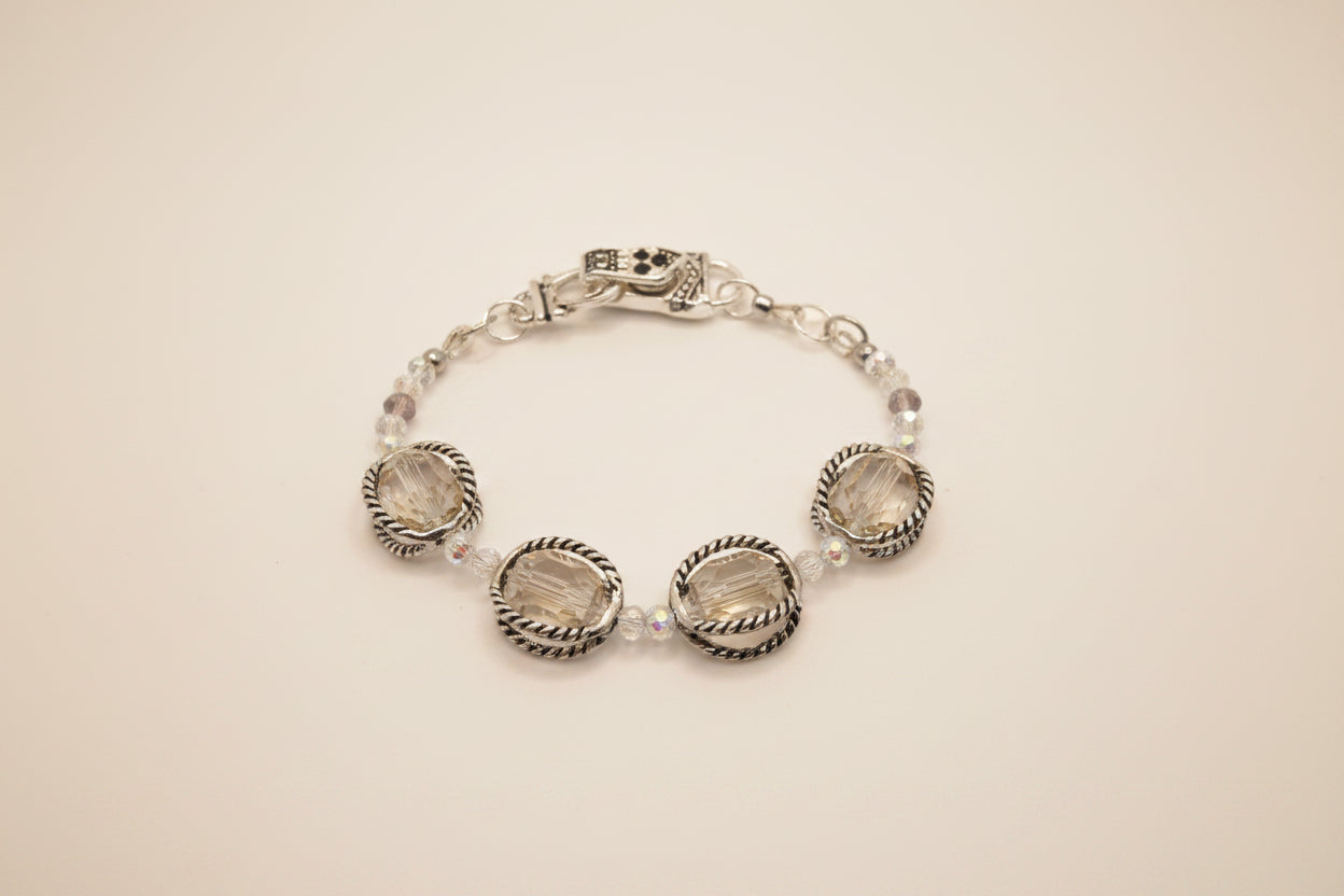 A silver-toned beaded bracelet with three large oval clear faceted gemstones and smaller clear beads, displayed on a neutral light gray background.