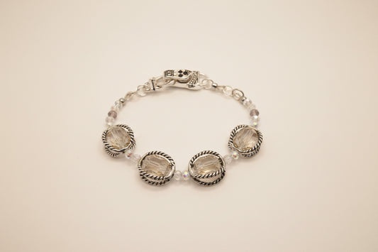 A silver-toned beaded bracelet with three large oval clear faceted gemstones and smaller clear beads, displayed on a neutral light gray background.
