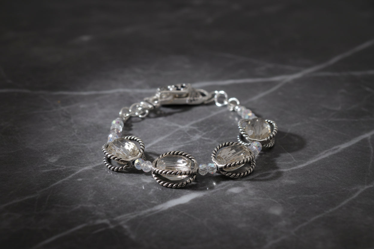 A silver-toned beaded bracelet featuring three large oval clear faceted crystals in textured silver settings, with small clear beads and a lobster clasp, shown on a plain light gray background.