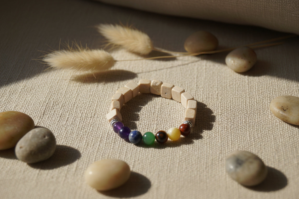 A beaded stretch bracelet made of light beige wooden cubes with a section of colorful rainbow beads, displayed on a plain light gray background.