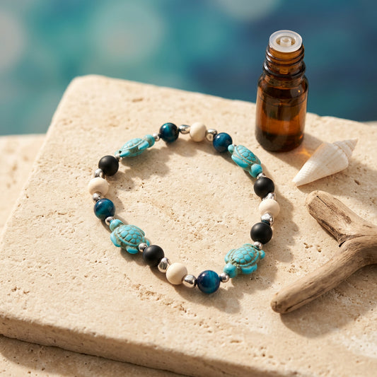 A beaded stretch bracelet featuring turquoise and blue beads, dark black beads, light beige wooden beads, and carved sea turtle beads, displayed on a neutral gray background.