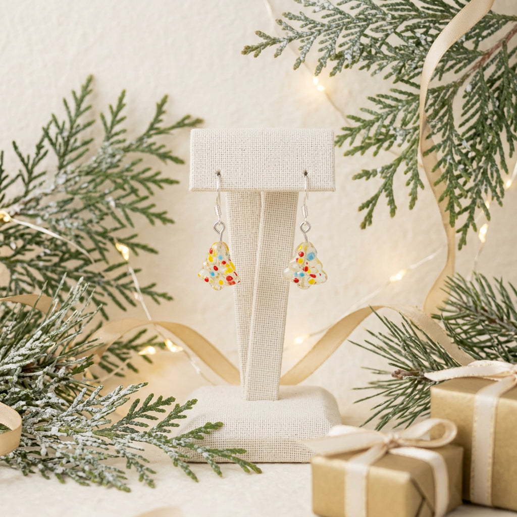A pair of small dangling earrings with colorful speckled translucent pieces and silver hooks, displayed on a clear stand against a plain light gray background.