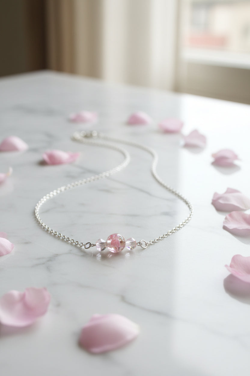 A silver chain necklace with a pink and clear bead pendant, displayed on a black velvet jewelry bust against a white background.