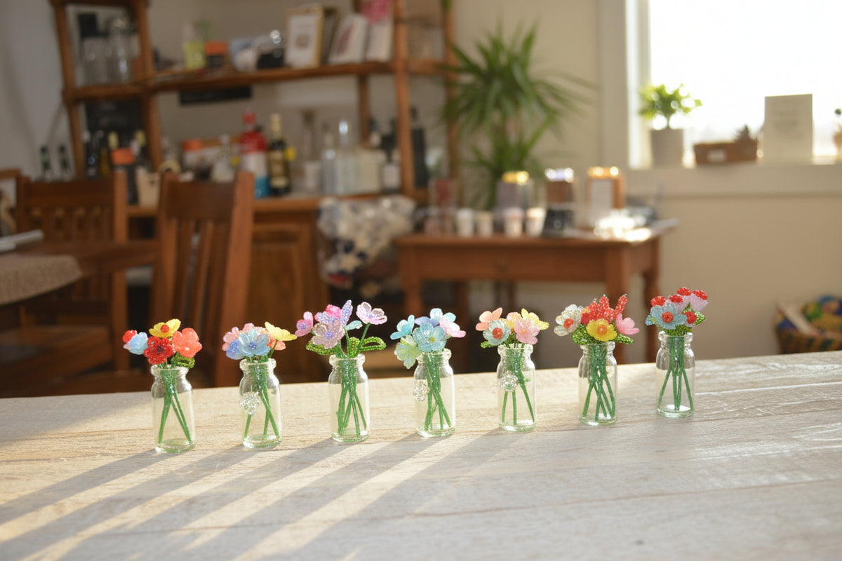 A display of decorative glassware and small floral arrangements in light natural wood crates on a dark floor, with more merchandise visible in the background.