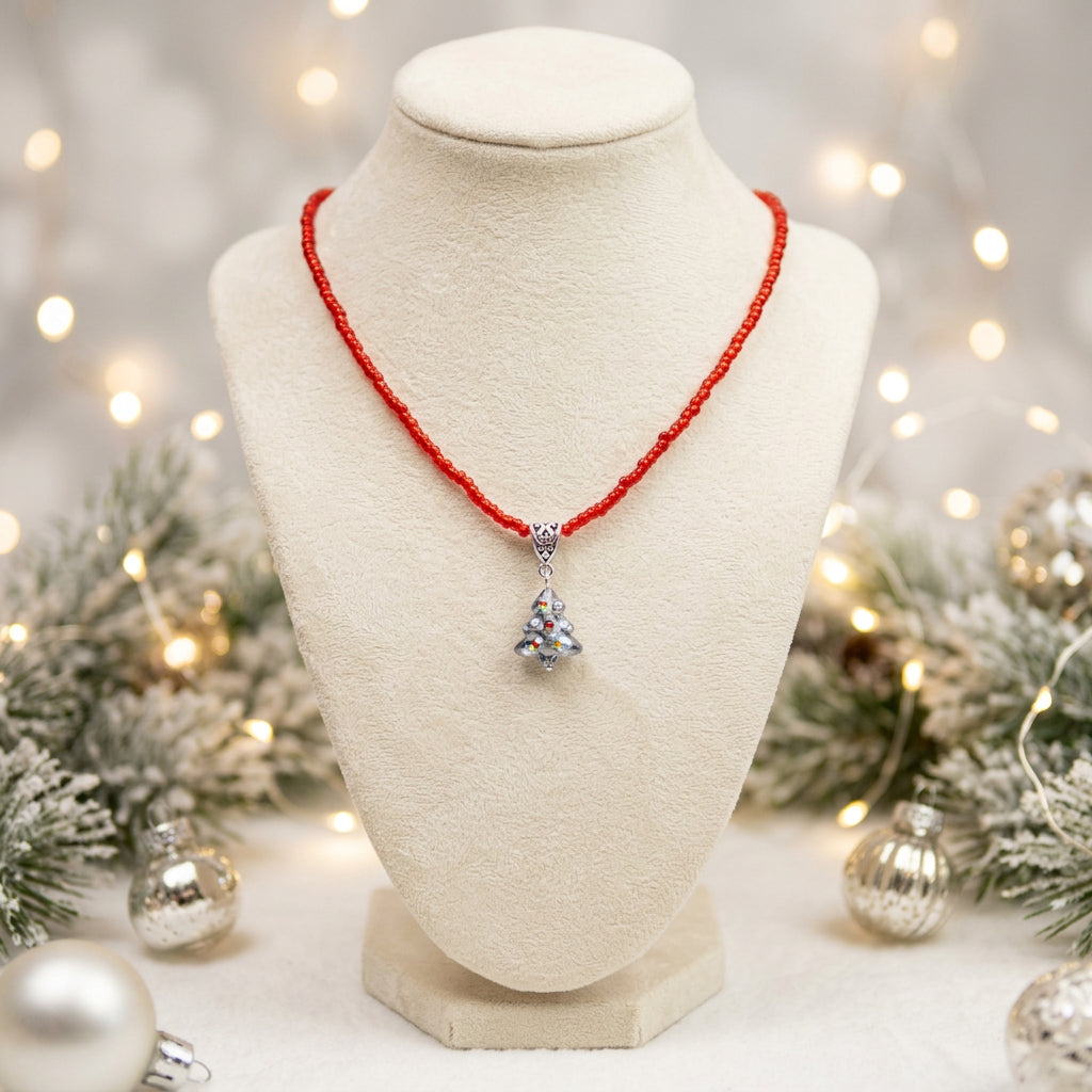 A red beaded necklace with a silver-toned pendant featuring a clear heart-shaped stone, displayed on a black jewelry bust against a white background.
