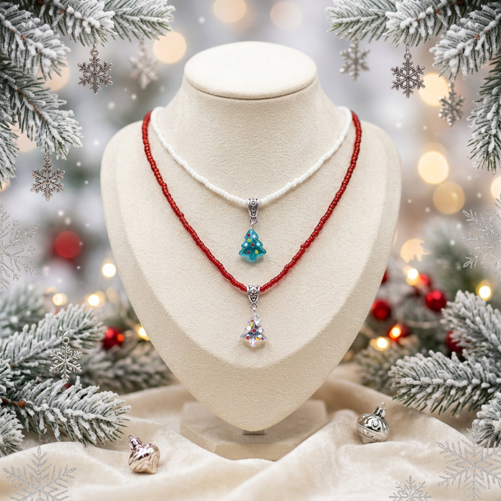 Two layered necklaces displayed on a black velvet jewelry bust against a white background. The top necklace is white with a small light blue Christmas tree pendant.