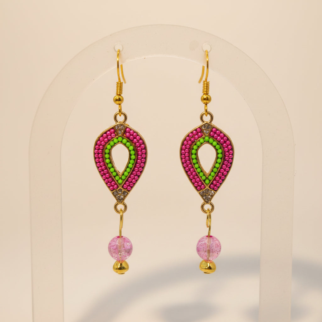 A pair of gold-tone dangle earrings with pink and green beaded teardrop-shaped charms and dangling pink faceted beads, displayed against a light gray background.