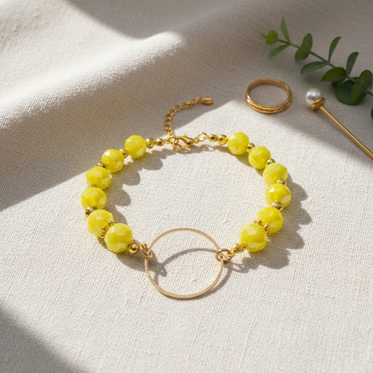A gold-tone bracelet featuring faceted lime green beads and a large open circular gold-tone ring clasp, displayed on a neutral light gray background.