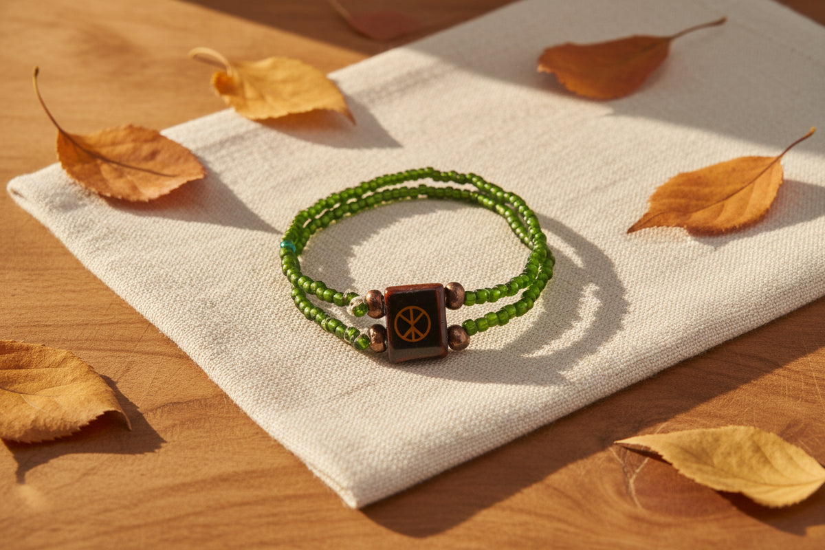 A double-strand beaded bracelet featuring olive green beads, small metallic bronze spacer beads, and a central dark brown square charm with a gold peace sign, displayed on a plain light gray background.
