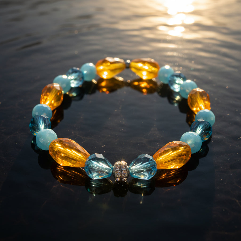 A beaded stretch bracelet featuring faceted light blue beads and translucent amber-yellow teardrop beads, separated by small silver spacer beads, with a central clear rhinestone accent.