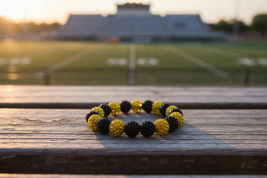 A beaded stretch bracelet featuring alternating black and gold rhinestone-covered round beads, displayed on a plain light gray background.