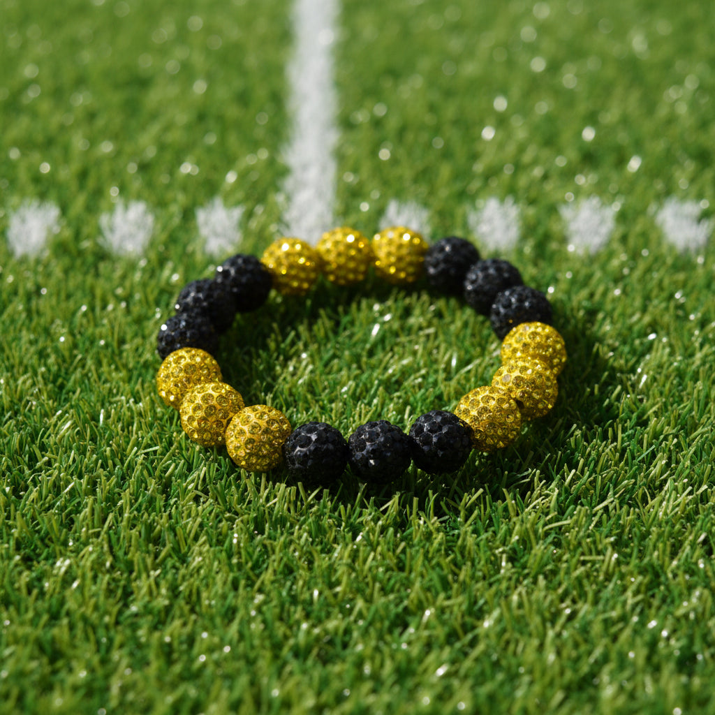 A beaded stretch bracelet featuring alternating textured black and shiny gold faceted beads, displayed on a neutral light gray background.