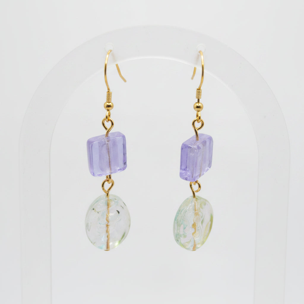 Pair of earrings with purple and green beads on a gray background